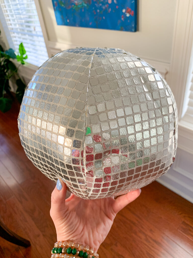 woman holds a disco ball pillow in hand