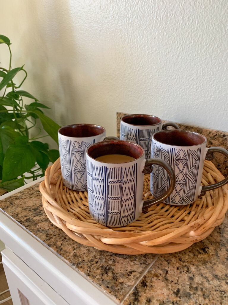 four tribal coffee mugs on a basket tray at a coffee and dessert party