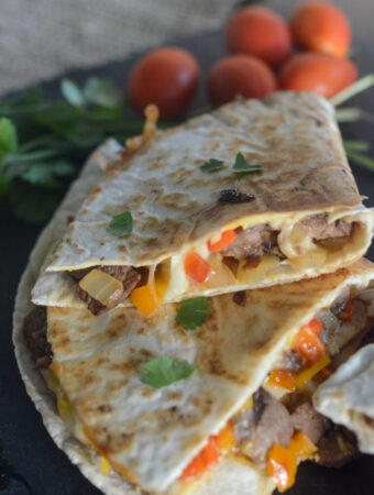 Philly steak quesadilla with leftover steak stacked on black tray