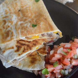 Philly cheese steak quesadilla recipe on black plate with pico