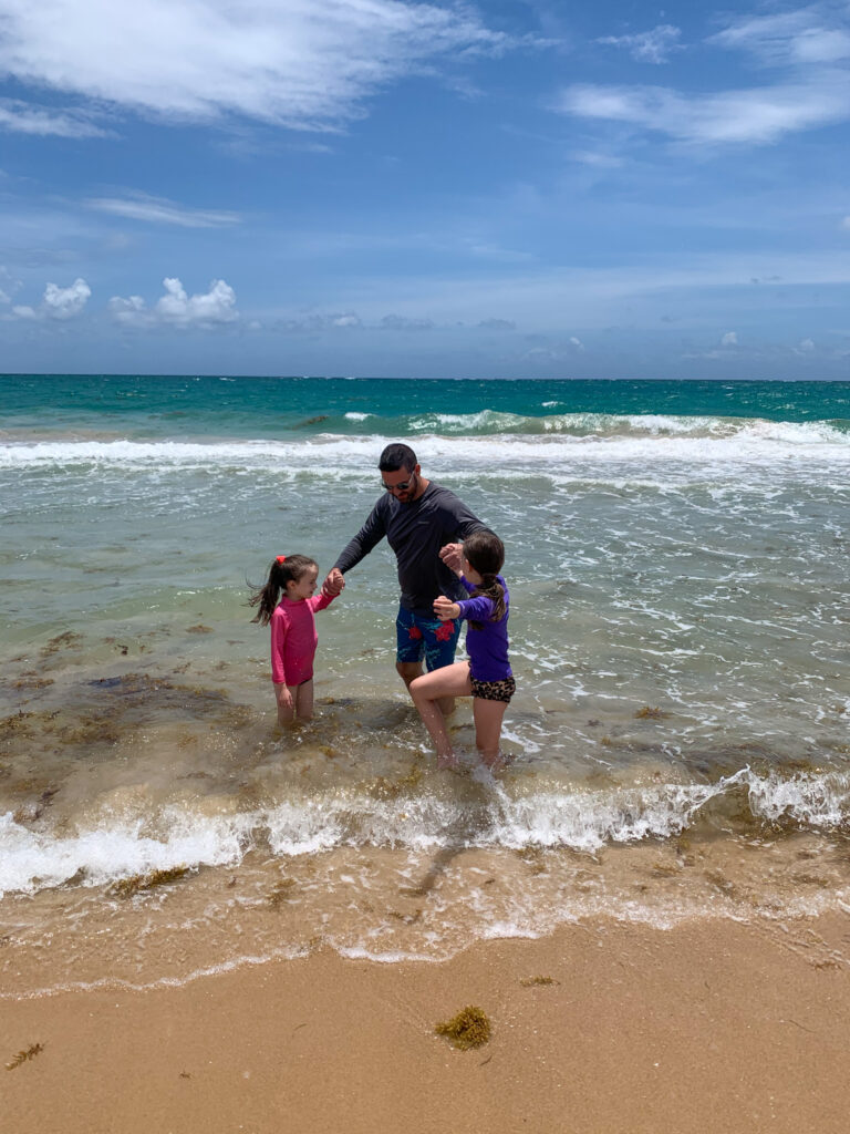 Dad and two daughters play in the water on Condado Beach