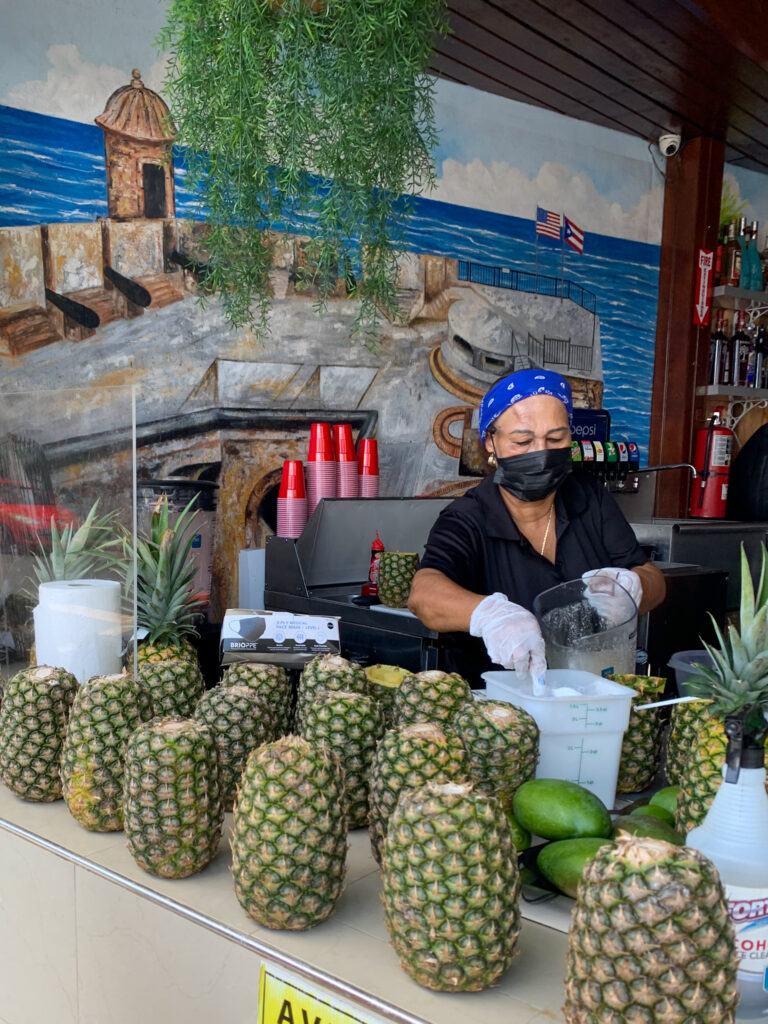 woman prepares piña coladas in pineapples at lunch restaurant in Condado