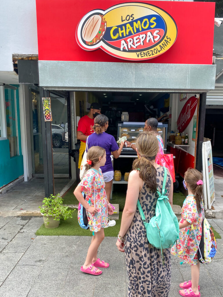 family waits in line for street food - Arepas - in San Juan