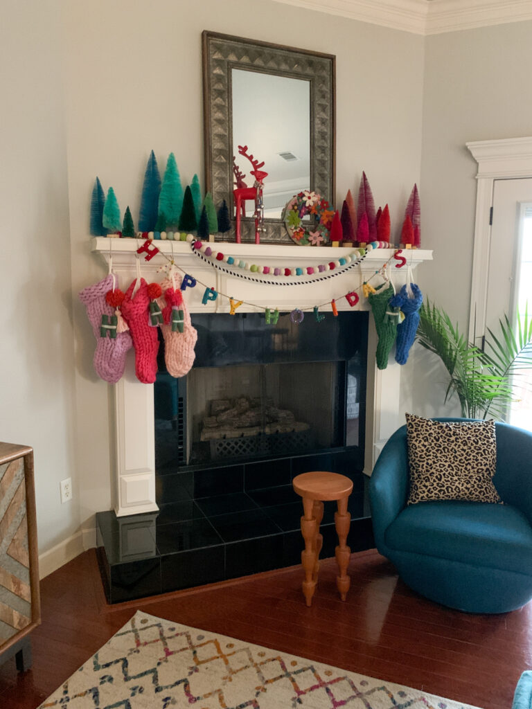 Merry and Bright Christmas decor mantle with knitted stockings and bottle brush trees