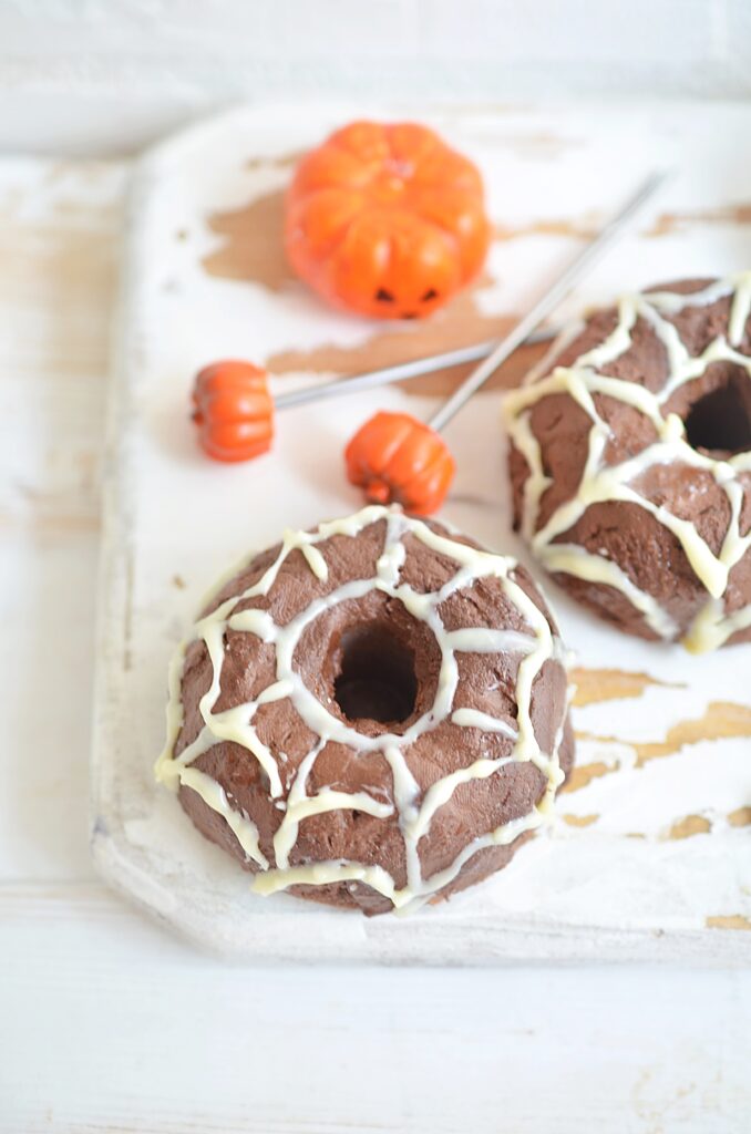 spider web donuts on white platter with small orange pumpkin picks
