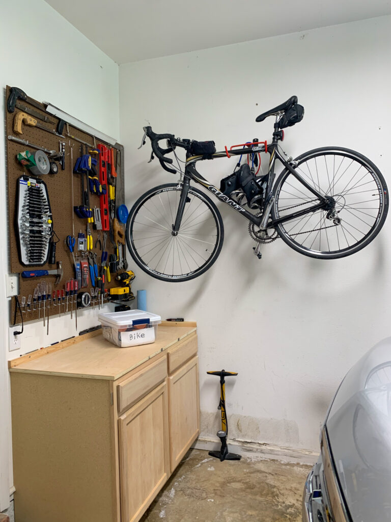 a wall bike mount holds a bike in a garage with more cycling essentials at left on counter