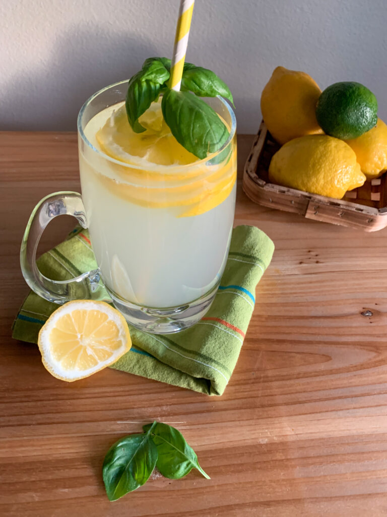 basil vodka lemonade in a mug with fresh lemons around