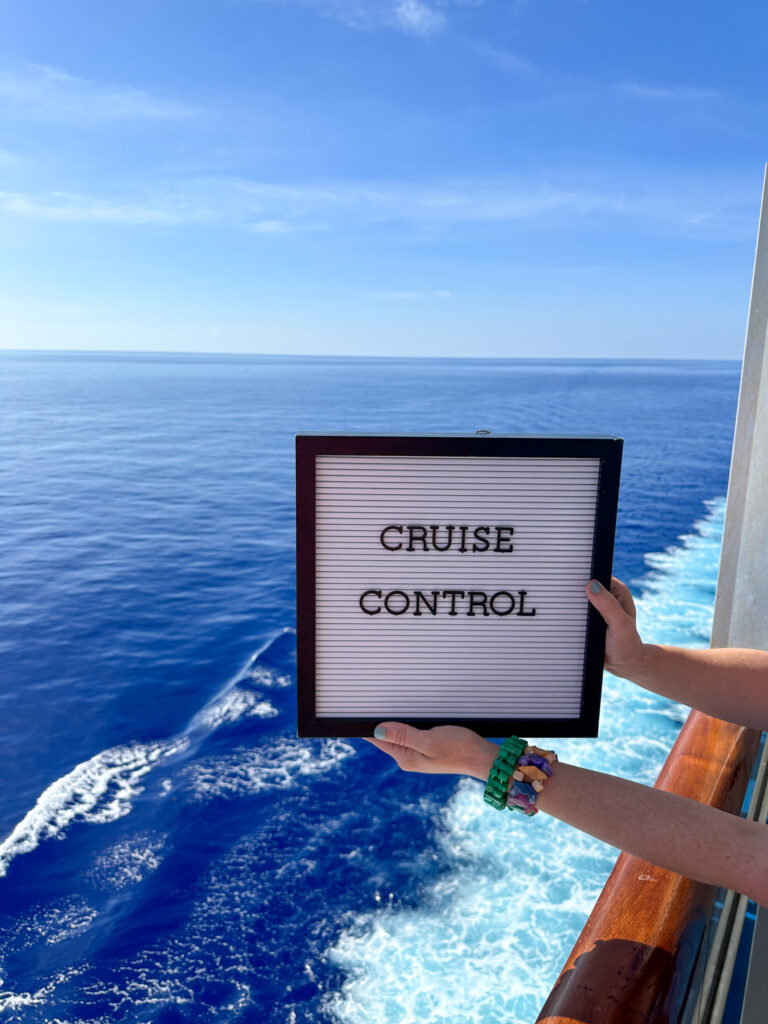 woman in cruise cabin balcony on Carnival Valor with cruise quotes on letter board