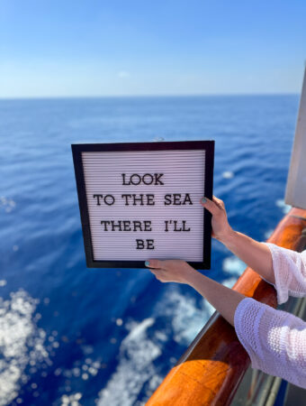 cruise quotes on letter board over a balcony on the ocean