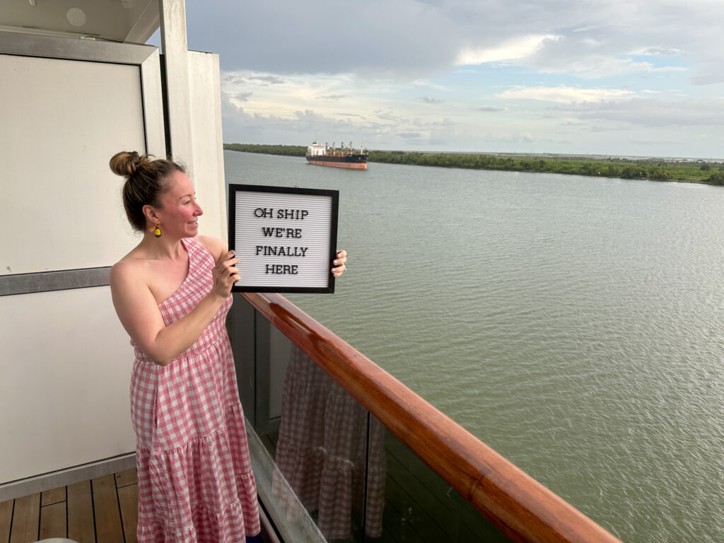 woman holds quotes about cruising letter board on her Carnival Valor cruise cabin over the Mississippi River