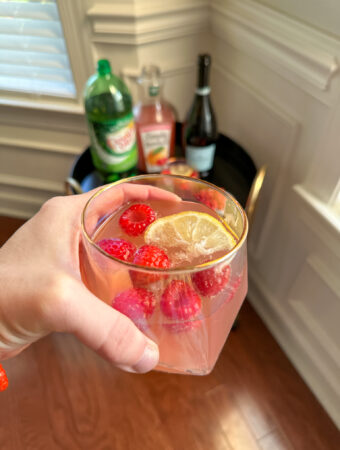 raspberry lemonade and ginger ale in woman's hand with bar tray in back
