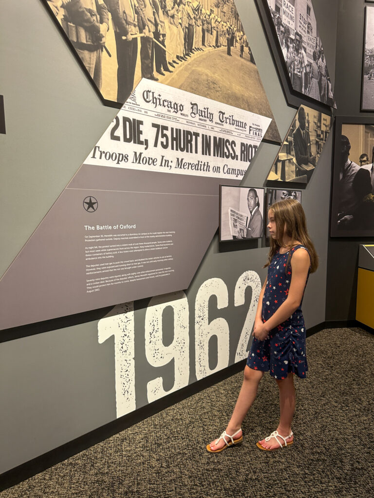 girl looks at James Meredith museum exhibit