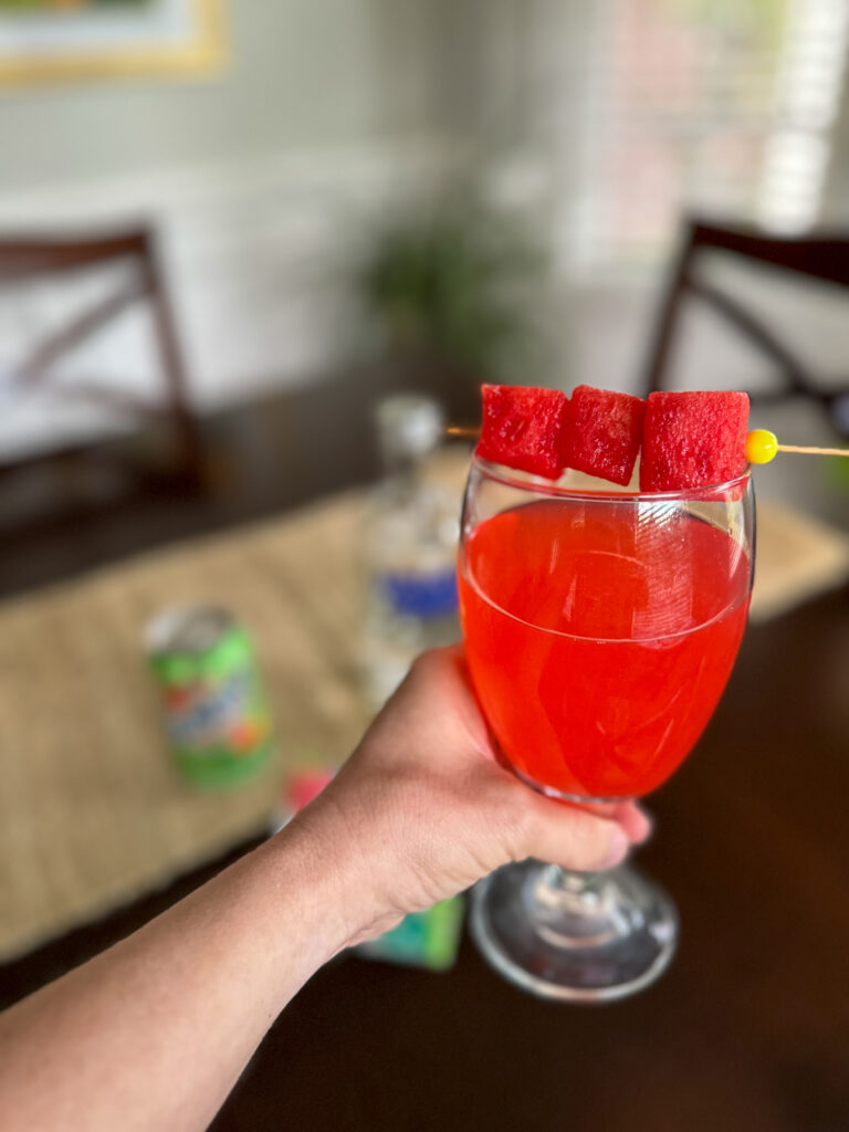 woman holds watermelon lemonade with vodka glass with a watermelon garnish on top