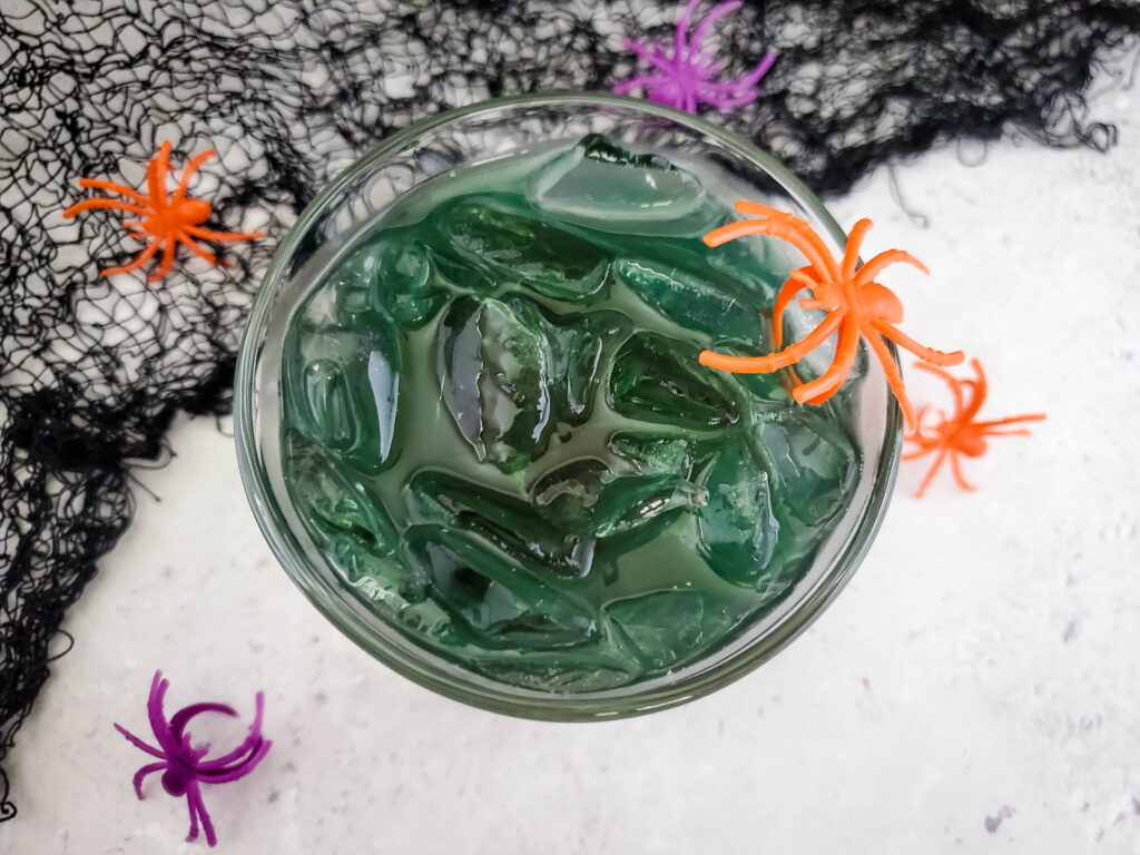 Dark Magic Halloween margarita with plastic spiders and black cobwebs to the back