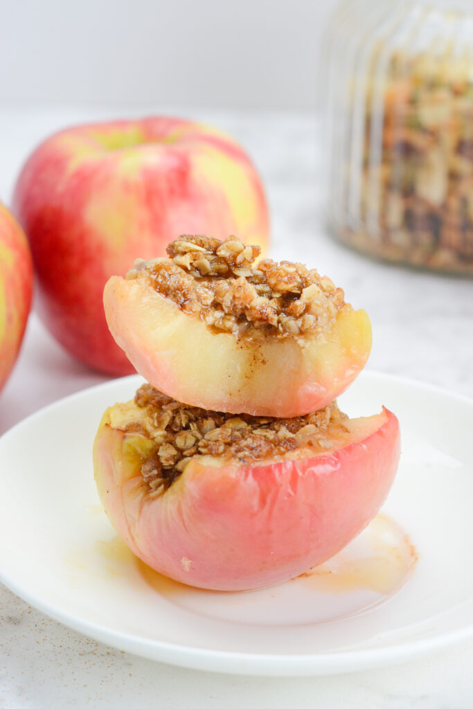 air fried apples with oat topping stacked on a plate with more apples at back