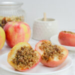 air fryer apples on a white serving plate with container of honey at back