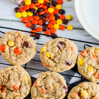 Reese's Pieces cookies with peanut butter on a baking rack with colorful candy at back