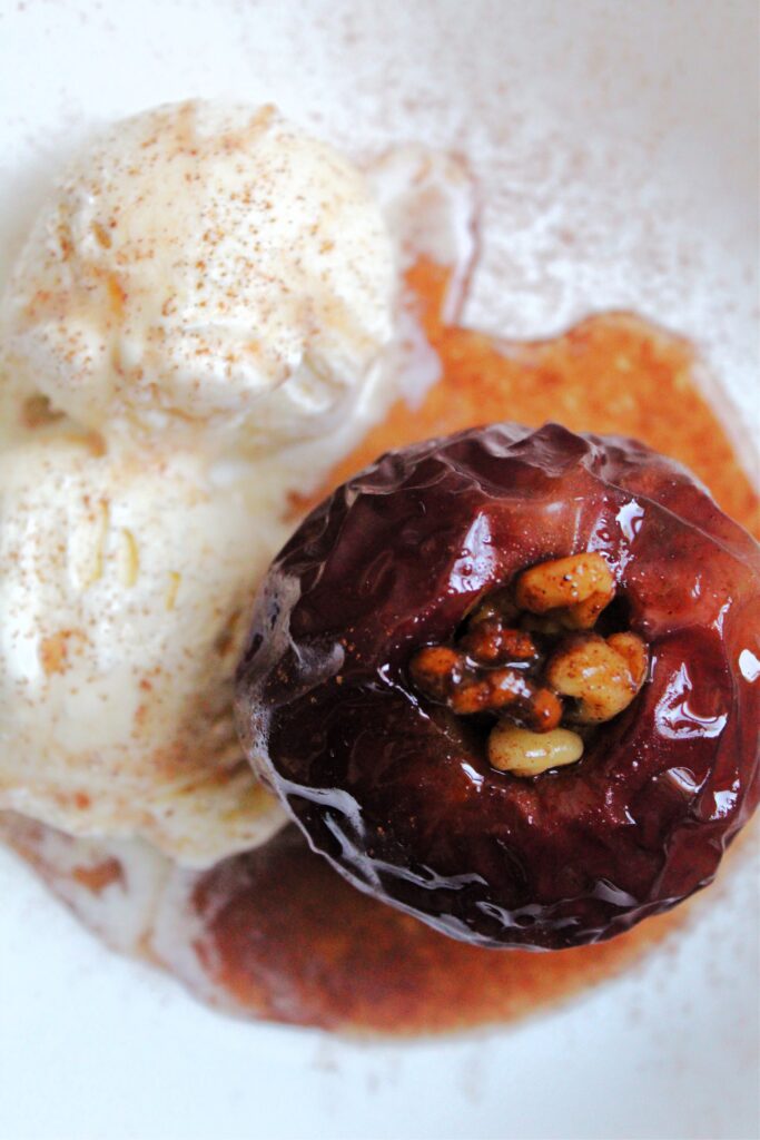 baked apples with walnuts beside scoops of ice cream