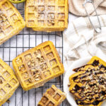 pumpkin pecan waffles scattered on a wire rack and piled on a white plate