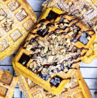 pumpkin waffles with pecans and chocolate drizzle on a baking rack