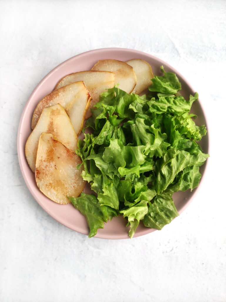 pears and spinach on plate for bottom layer of salad