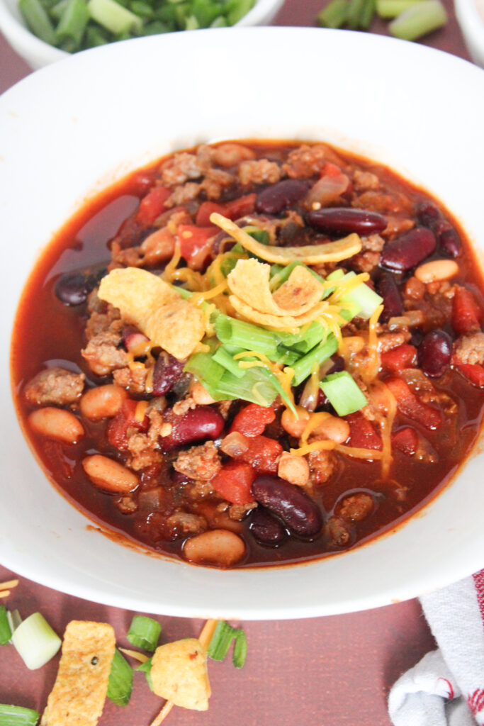 overhead view of beef and sausage chili in white bowl