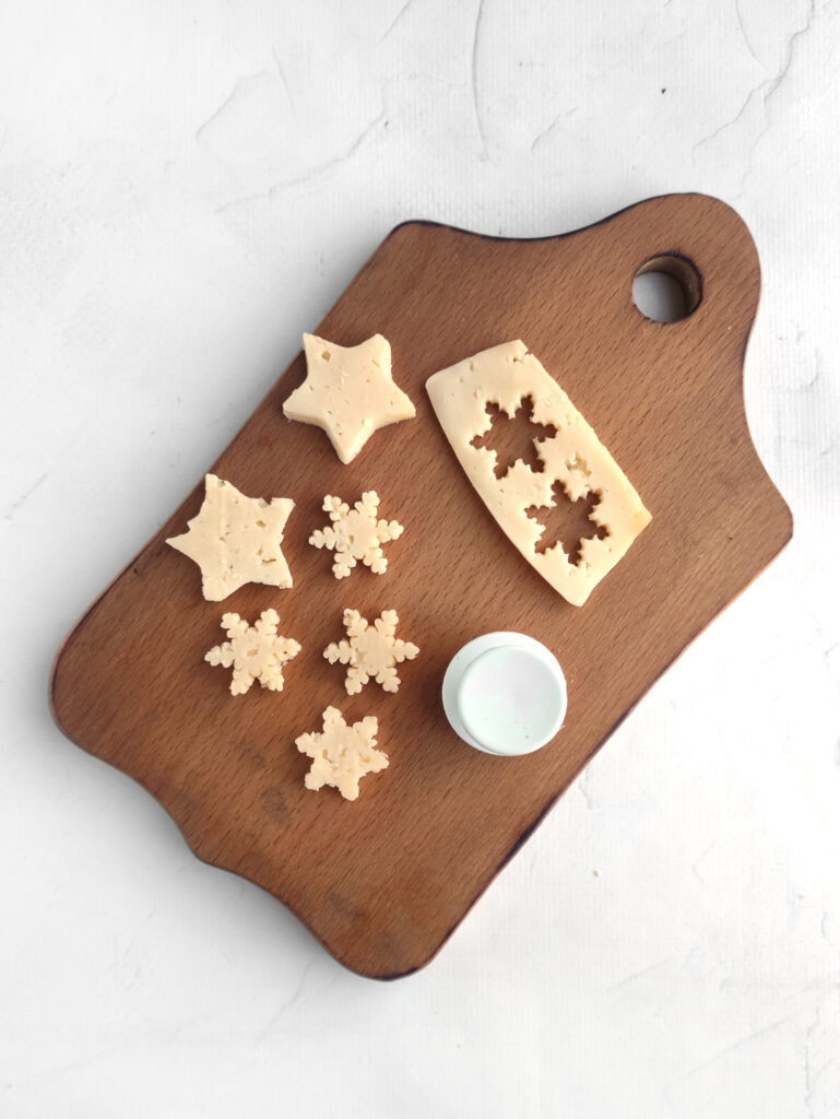 snowflakes and stars cheese cut from cookie cutters on wood 