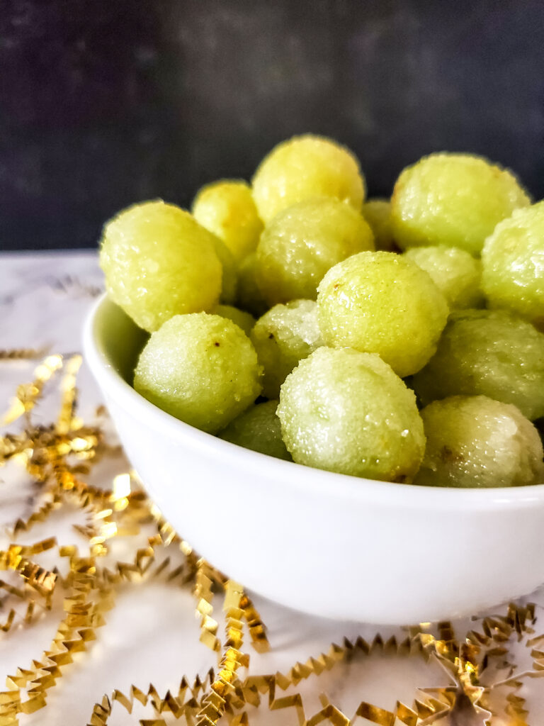 sugared frozen grapes in a white bowl with a black background