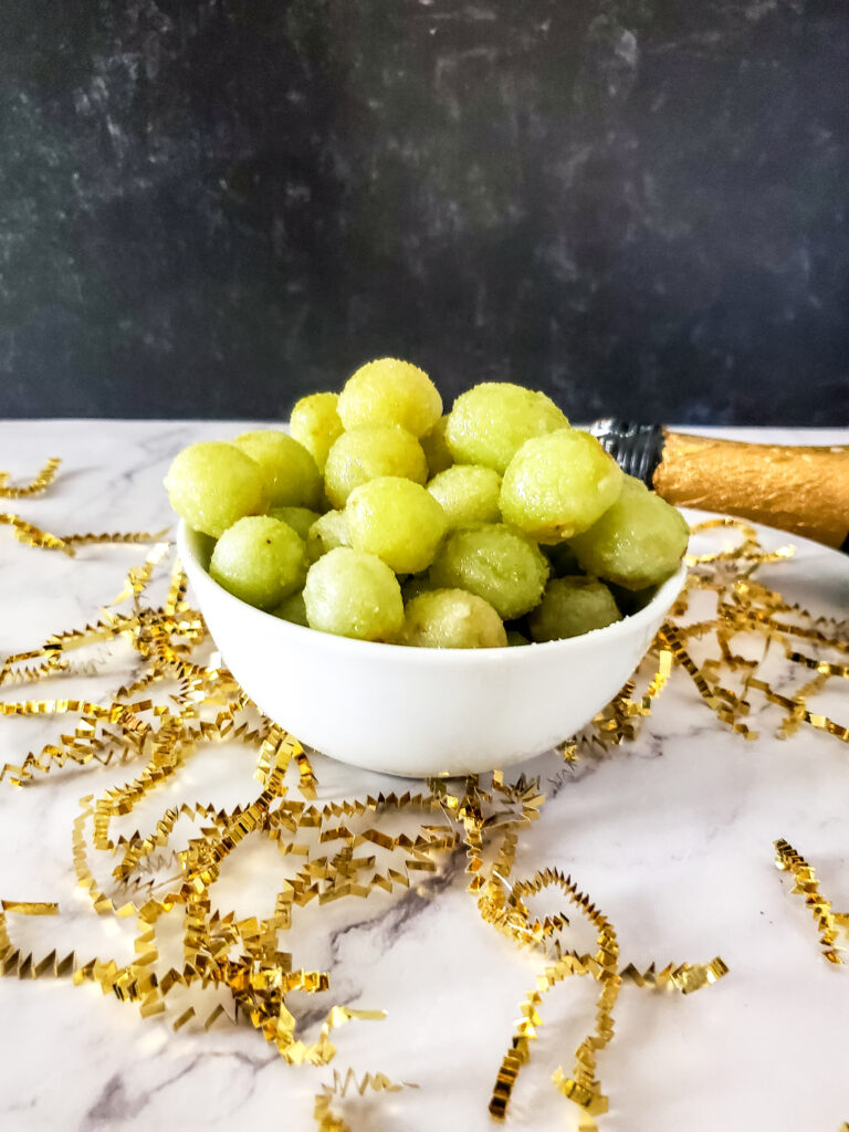 sugared frozen grapes with sparkling wine bottle at back
