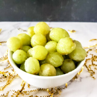 sugared champagne grapes in white bowl with confetti around