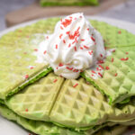 green waffles on plate with sprinkles and whipped cream