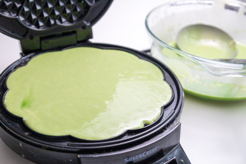 green waffle cooking in waffle maker