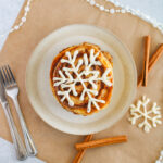 cinnamon swirl pancakes with cream cheese icing - snowflake pancakes on plate on parchment paper