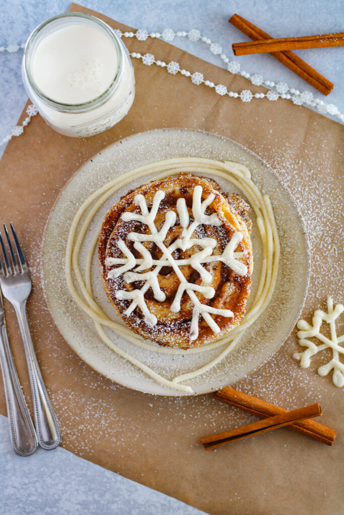 cinnamon swirl pancakes with snowflake icing made with cream cheese on brown place setting