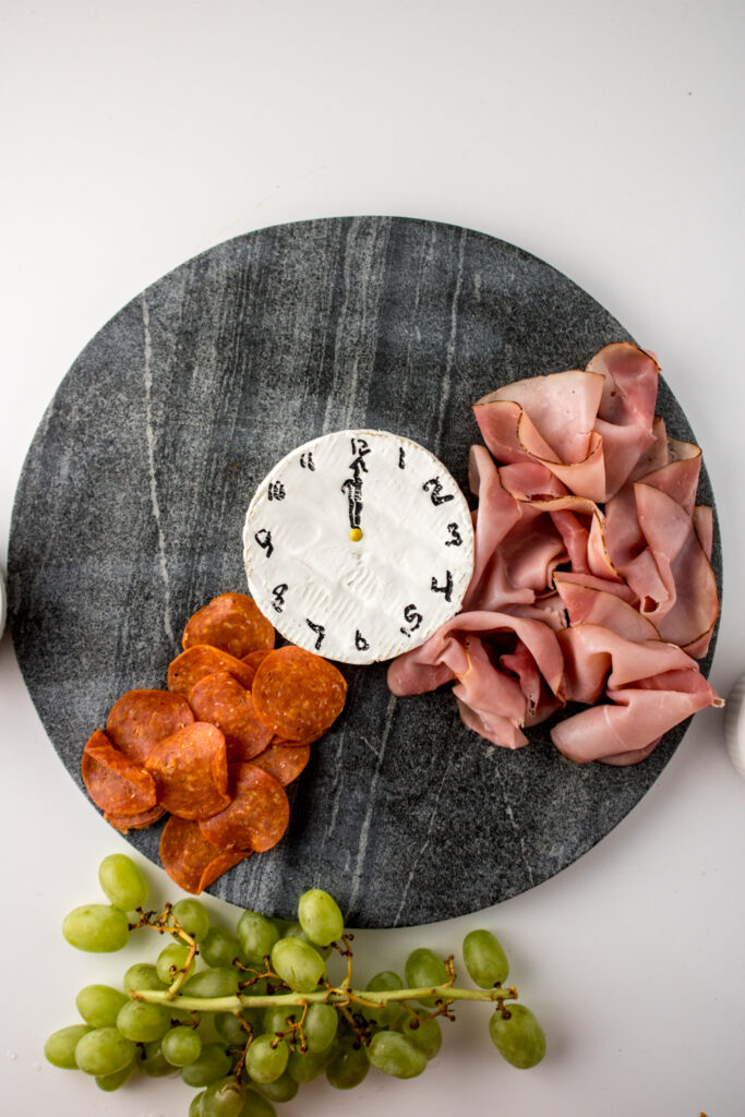 ham folded around a cheese clock on the start of a New Year's charcuterie board