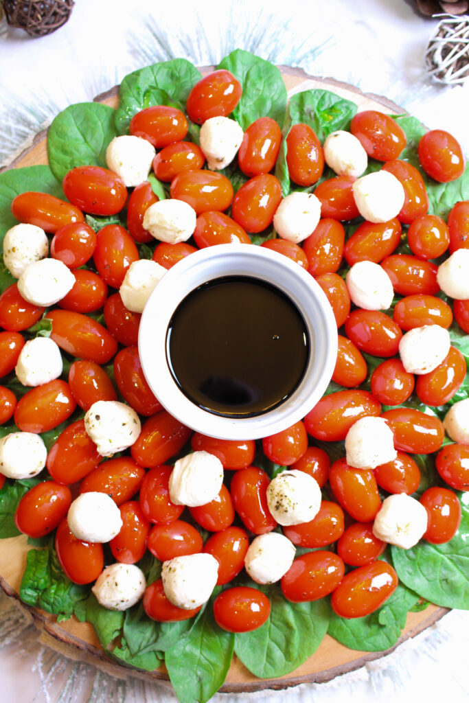 caprese wreath salad for Christmas with bowl of balsamic vinegar in center