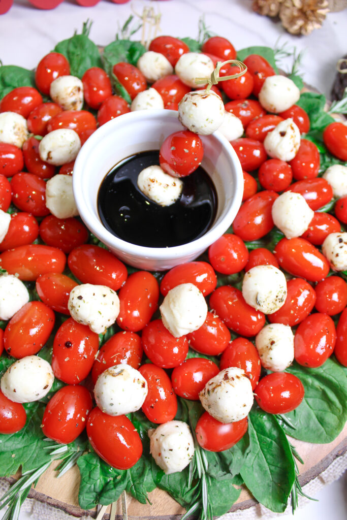 Caprese Christmas wreath salad with a Caprese skewer in balsamic vinegar in center of bowl