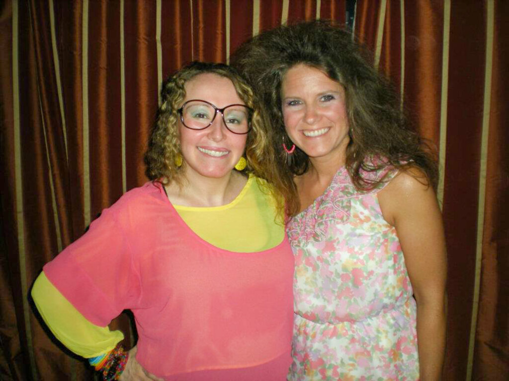two ladies dressed in 1980s costumes for 80s murder mystery party