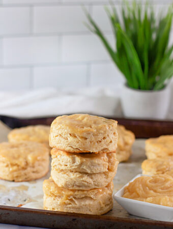 cream cheese biscuits with honey butter glaze stacked on a baking sheet