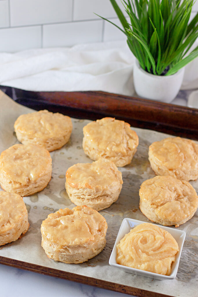 tray of homemade honey butter biscuits with honey butter sauce in bowl