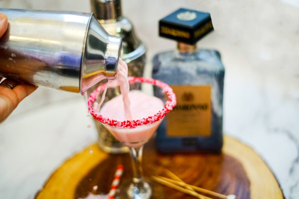 pink martini pouring into glass rimmed with sprinkles