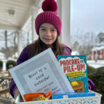 little girl holds snow box gift in front of snowy street
