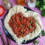 date night spaghetti shaped like a heart on black plate and plaid napkin