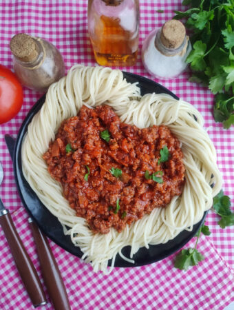 date night spaghetti shaped like a heart on black plate and plaid napkin