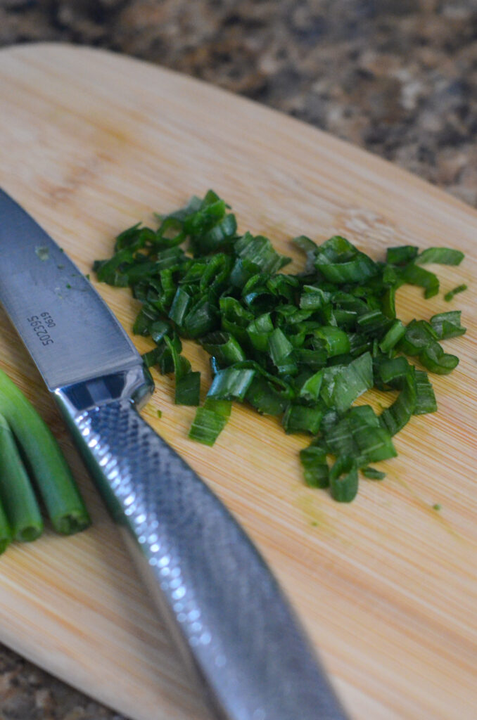 green onions being chopped on cutting board