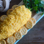 springtime carrot-shaped cheese ball on a bread board with crackers around