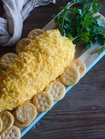 springtime carrot-shaped cheese ball on a bread board with crackers around