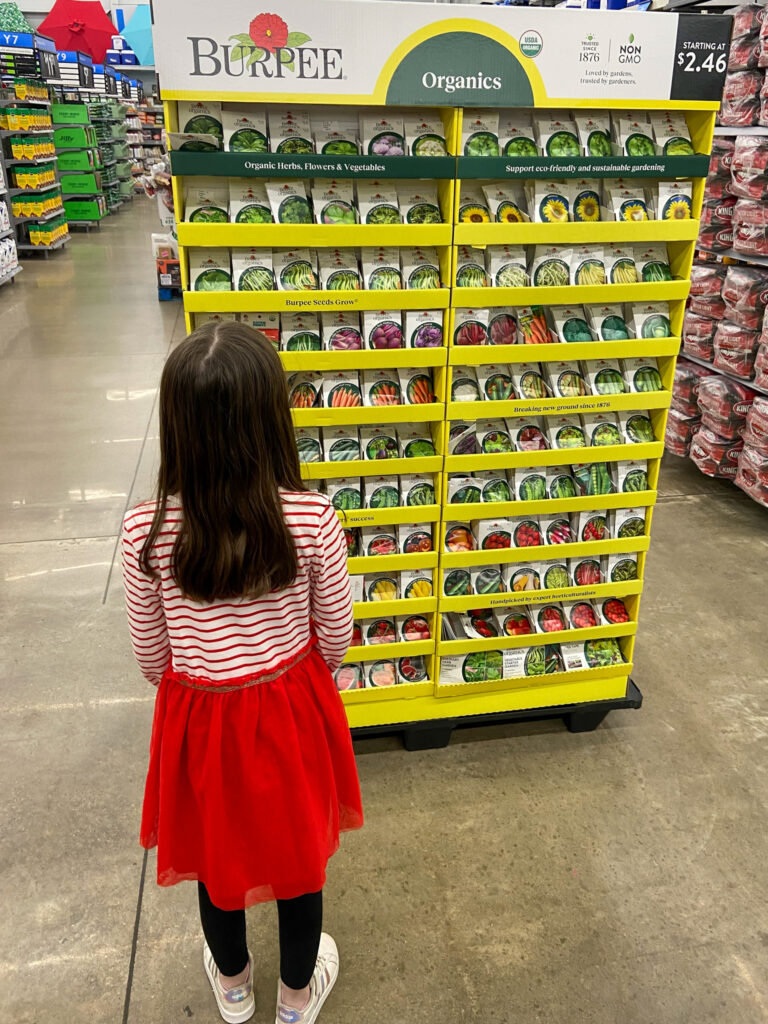 little girl looks at gardening items at Walmart