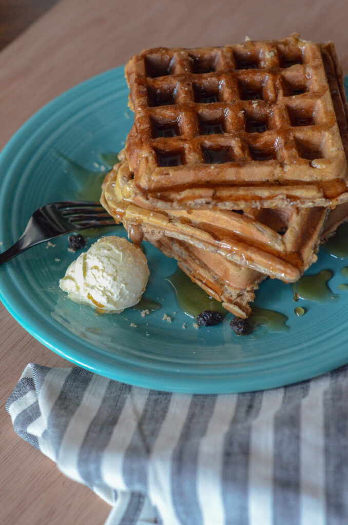 oatmeal raisin waffles on teal plate with a scoop of butter at side