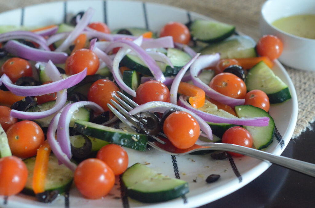 Mediterranean cucumber tomato salad with fork on plate